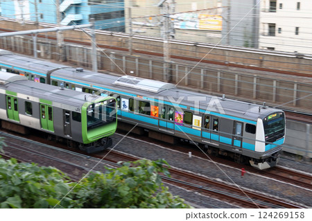 The Yamanote Line E235 Series train and the Keihin Tohoku Line E233 Series train run parallel to each other. 124269158