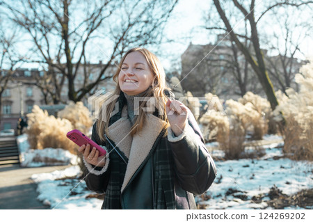 Portrait of happy woman enjoying winter moments with phone  124269202