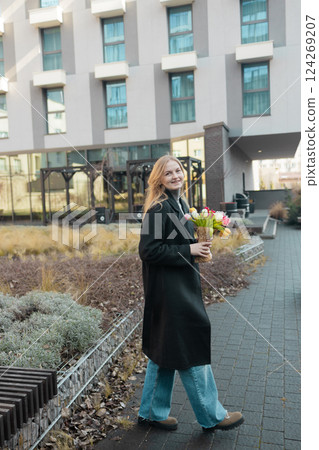 Happy International Women's Day Concept. Beautiful happy Caucasian woman smelling bunch of tulips with closed eyes 124269207