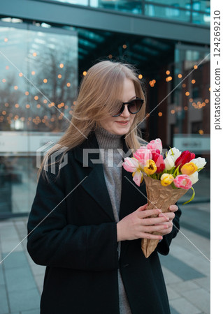 Happy International Women's Day Concept. Beautiful happy Caucasian woman smelling bunch of tulips with closed eyes 124269210