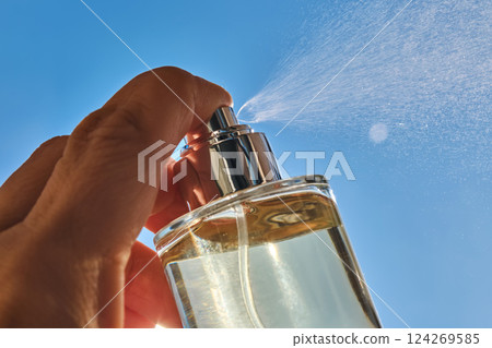 Spraying perfume against the sky. 124269585