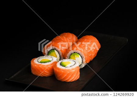 Delicious Fresh Salmon Sushi Rolls Presenting Exquisitely on a Black Background 124269920