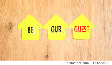 Be our guest symbol. Concept words Be our guest on beautiful yellow paper houses. Beautiful wooden background. Business and be our guest concept. Copy space. 124270159