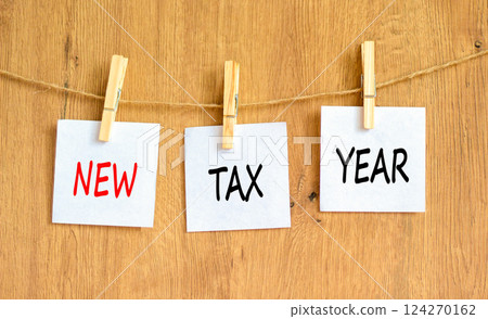 New tax year symbol. Concept words New tax year on beautiful white paper on clothespin. Beautiful wooden background. Business new tax year concept. Copy space. New tax year symbol. Concept words New tax year on beautiful white paper on clothespin. Beautiful wooden background. Business new tax year concept. Copy space. 124270162
