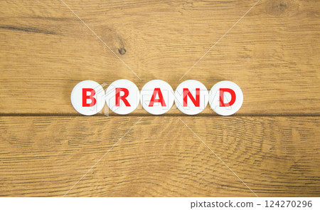 Brand symbol. Concept word Brand on beautiful white pills circles. Beautiful wooden table wooden background. Business brand concept. Copy space. Brand symbol. Concept word Brand on beautiful white pills circles. Beautiful wooden table wooden background. Business brand concept. Copy space. 124270296