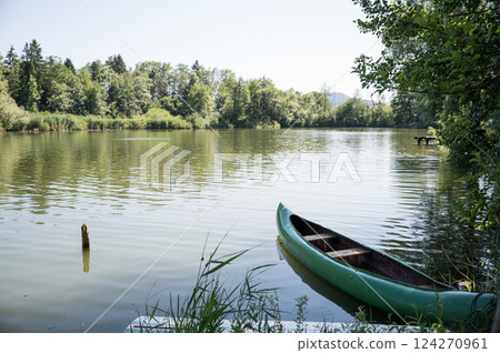 Green canoe boat parked by a lake shore Green canoe boat parked by a lake shore 124270961