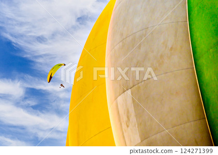 Paragliding in a blue sky with clouds and a yellow hot air balloon in the background. 124271399
