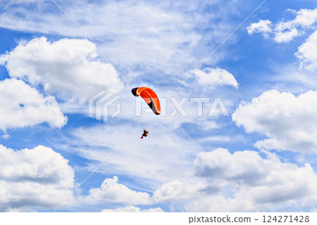 Paragliding adventure with a red and blue parachute on a sunny day. 124271428