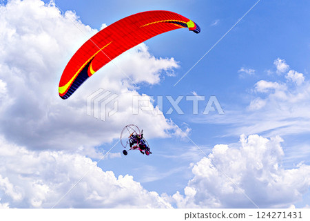 Paragliding adventure with a red and blue parachute on a sunny day. Paragliding adventure with a red and blue parachute on a sunny day. 124271431