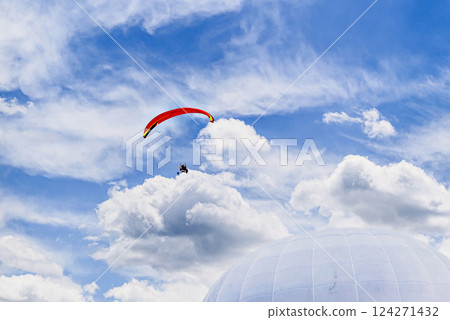 Paragliding adventure with a red and blue parachute on a sunny day. Paragliding adventure with a red and blue parachute on a sunny day. 124271432