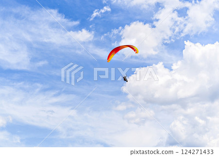 Paragliding adventure with a red and blue parachute on a sunny day. Paragliding adventure with a red and blue parachute on a sunny day. 124271433
