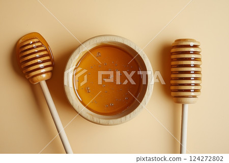 Wooden honey dipper and bowl of pure golden honey on neutral background 124272802