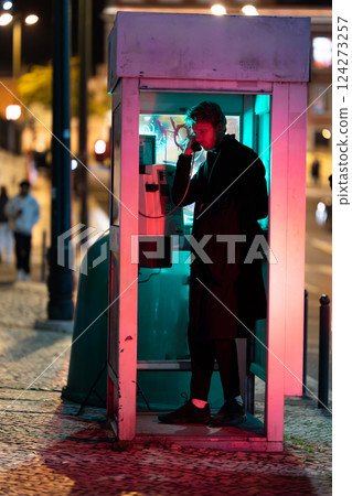 A young man is talking on a phone at noir style in booth A young man is talking on a phone at noir style in booth 124273257