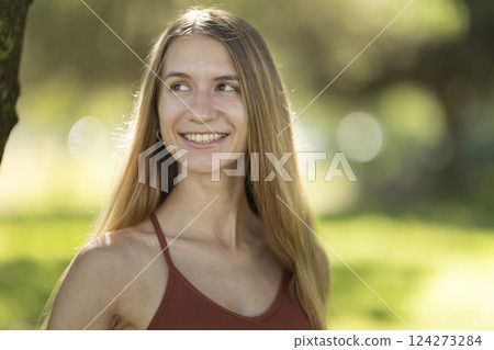 Young woman smiling and looking away in the park 124273284