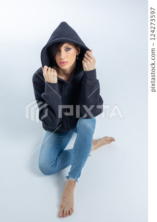 Portrait beautiful woman of model appearance. Girl in black sweatshirt on grey background. Pretty female with trendy makeup posing in studio. Vertical photo. High quality photo 124273597