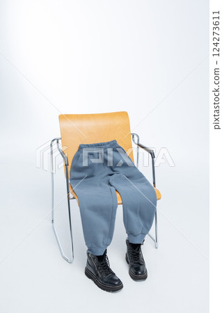 Gray sweatpants with black boots lying on wooden chair on light background. Vertical photo. High quality photo Gray sweatpants with black boots lying on wooden chair on light background. Vertical photo. High quality photo 124273611