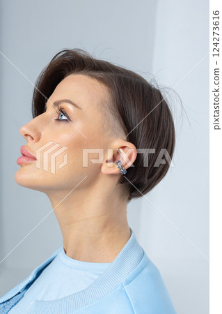 Close-up of girl's earring in her ear. Beautiful jewelry women's decoration. Studio photography. Vertical photo. High quality photo 124273616