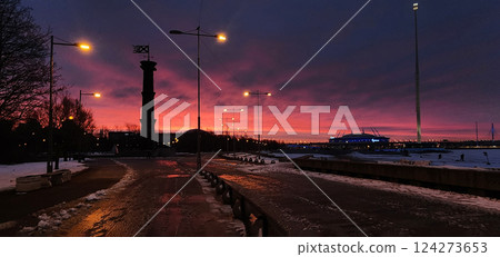 Panoramic view of winter landscape at fiery dawn. Silhouette of lighthouse and walking paths in park 300 anniversary of St. Petersburg, Russia. Panoramic view of winter landscape at fiery dawn. Silhouette of lighthouse and walking paths in park 300 anniversary of St. Petersburg, Russia. 124273653