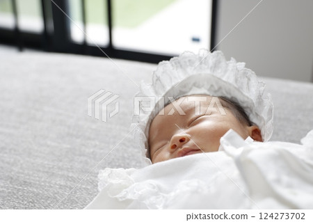一個穿著嬰兒服的新生嬰兒正在窗邊睡覺 一個穿著嬰兒服的新生嬰兒正在窗邊睡覺 124273702