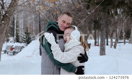 Loving couple hugging tenderly, standing close in snow blanketed winter park, surrounded by frost covered trees, capturing intimate romantic moment Loving couple hugging tenderly, standing close in snow blanketed winter park, surrounded by frost covered trees, capturing intimate romantic moment 124273976