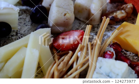 Rustic wooden board displaying artisan cheese varieties, accompanied by crisp breadsticks, vibrant grapes, ripe strawberries, and toasted nuts. Elegant appetizer presentation Rustic wooden board displaying artisan cheese varieties, accompanied by crisp breadsticks, vibrant grapes, ripe strawberries, and toasted nuts. Elegant appetizer presentation 124273977