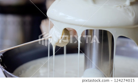 White chocolate streaming over wooden skewer, dripping smoothly onto ripe banana slice, delivering luxurious sweet moment 124274015