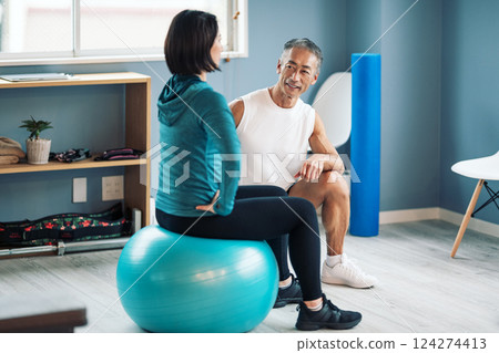 Trainer instructing balance ball at a sports gym 124274413
