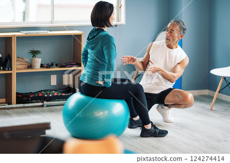 Trainer instructing balance ball at a sports gym 124274414