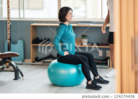A woman goes to the gym and trains her core with a balance ball A woman goes to the gym and trains her core with a balance ball 124274436