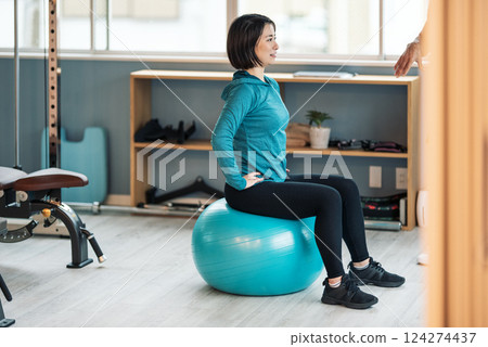 A woman goes to the gym and trains her core with a balance ball A woman goes to the gym and trains her core with a balance ball 124274437