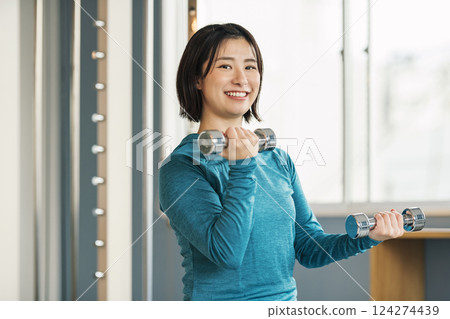 Woman doing muscle training using iron array at gym 124274439