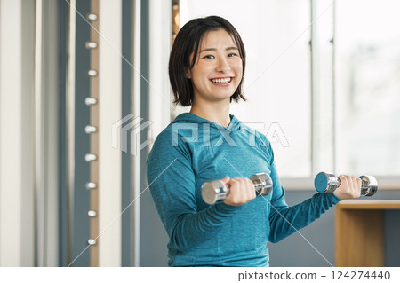 做肌肉訓練的婦女使用鐵列陣在健身房 做肌肉訓練的婦女使用鐵列陣在健身房 124274440