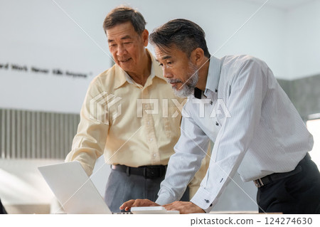 Consultation and Review. A senior man and a consultant collaborating over a laptop for strategic business planning. 124274630
