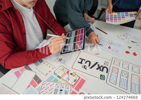 Creative Collaboration and Design Prototyping. Team members engaged in a lively session, refining design ideas using digital tools and paper prototypes. 124274668