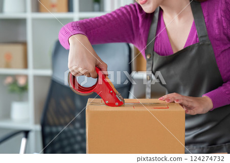 Sealing Packages for Shipment. An online seller using tape to secure a box. Sealing Packages for Shipment. An online seller using tape to secure a box. 124274732