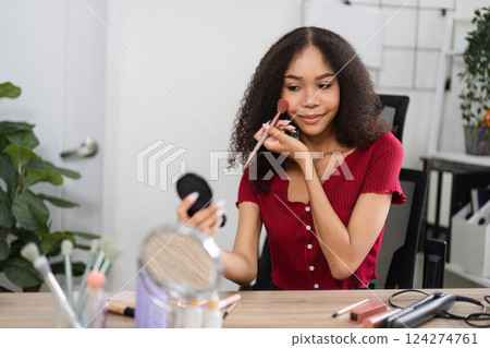 Natural Beauty and Skin Positivity. A woman skillfully applying blush while reflecting on her beauty. 124274761
