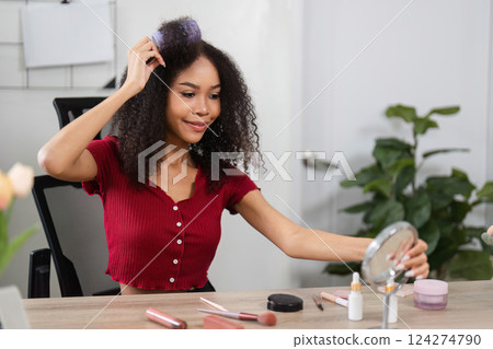 Natural Beauty and Skin Positivity. A delighted woman using cosmetics while emphasizing her beautiful curls. 124274790