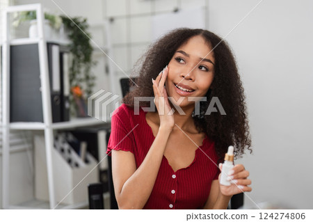 Natural Beauty and Skin Positivity. A woman cheerfully applying skincare while embracing her natural look. 124274806