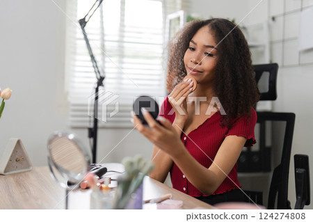 Natural Beauty and Skin Positivity. A woman thoughtfully applying skincare while admiring her appearance. 124274808