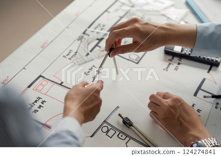 Collaboration and Precision. Close-up of professionals working together on architectural plans with compasses and rulers. Collaboration and Precision. Close-up of professionals working together on architectural plans with compasses and rulers. 124274841