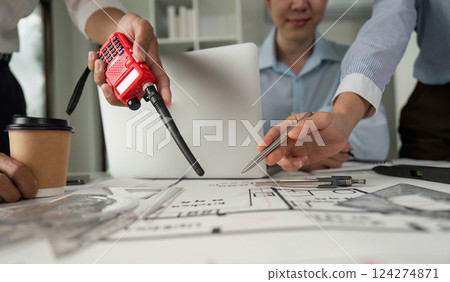 Communication and Coordination. Team members discussing architectural plans using walkie-talkies for effective collaboration. 124274871