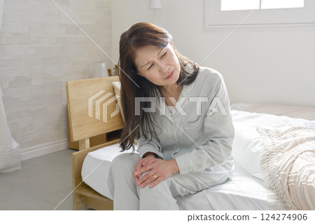 Middle-aged woman in pajamas with painful knee 124274906
