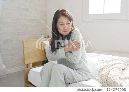 Middle-aged woman in pajamas feeling cold Middle-aged woman in pajamas feeling cold 124274908