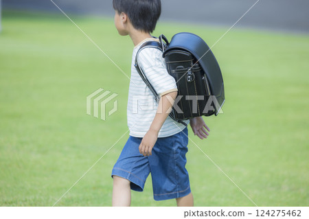 Elementary school student carrying a backpack walking outdoors Elementary school student carrying a backpack walking outdoors 124275462