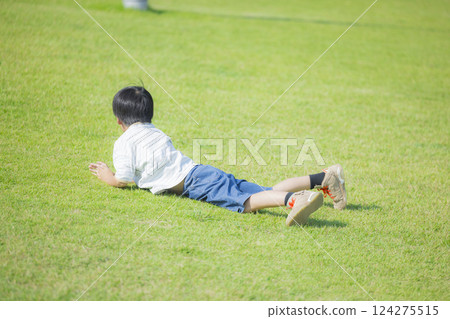 A boy lying down on the lawn 124275515