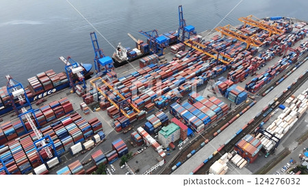 Aerial view of a cargo ship being loaded with colorful shipping containers at a bustling commercial port, showcasing global trade and logistics 124276032