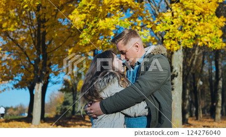 Loving couple hugging among golden leaved trees during bright autumn afternoon Loving couple hugging among golden leaved trees during bright autumn afternoon 124276040