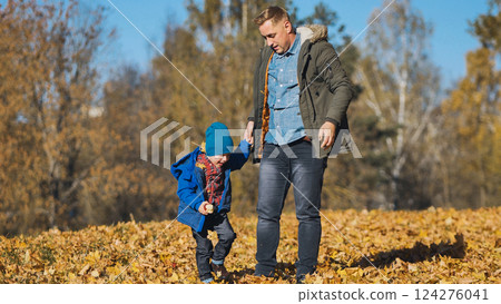 Father walking with son through park, sharing moment amid golden autumn foliage and scattered crisp leaves Father walking with son through park, sharing moment amid golden autumn foliage and scattered crisp leaves 124276041