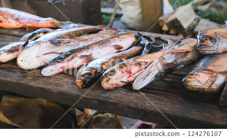 Variety of freshly caught fish displayed on a rustic wooden table, ready for preparation or sale in an outdoor setting Variety of freshly caught fish displayed on a rustic wooden table, ready for preparation or sale in an outdoor setting 124276107