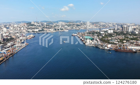 Aerial panorama capturing vladivostok's zolotoy rog bay, featuring industrial vessels, cable stayed zolotoy bridge gleaming under bright sunlight Aerial panorama capturing vladivostok's zolotoy rog bay, featuring industrial vessels, cable stayed zolotoy bridge gleaming under bright sunlight 124276180